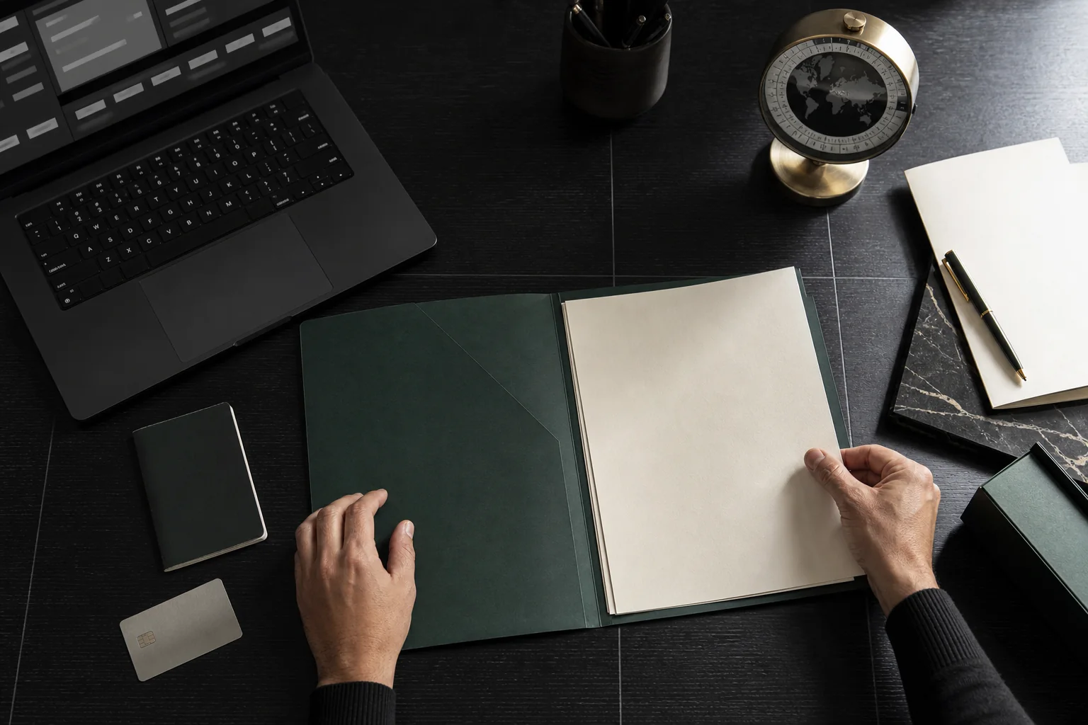 Mesa de trabajo con documentos, ordenador y reloj mundial para coordinar una operación internacional.